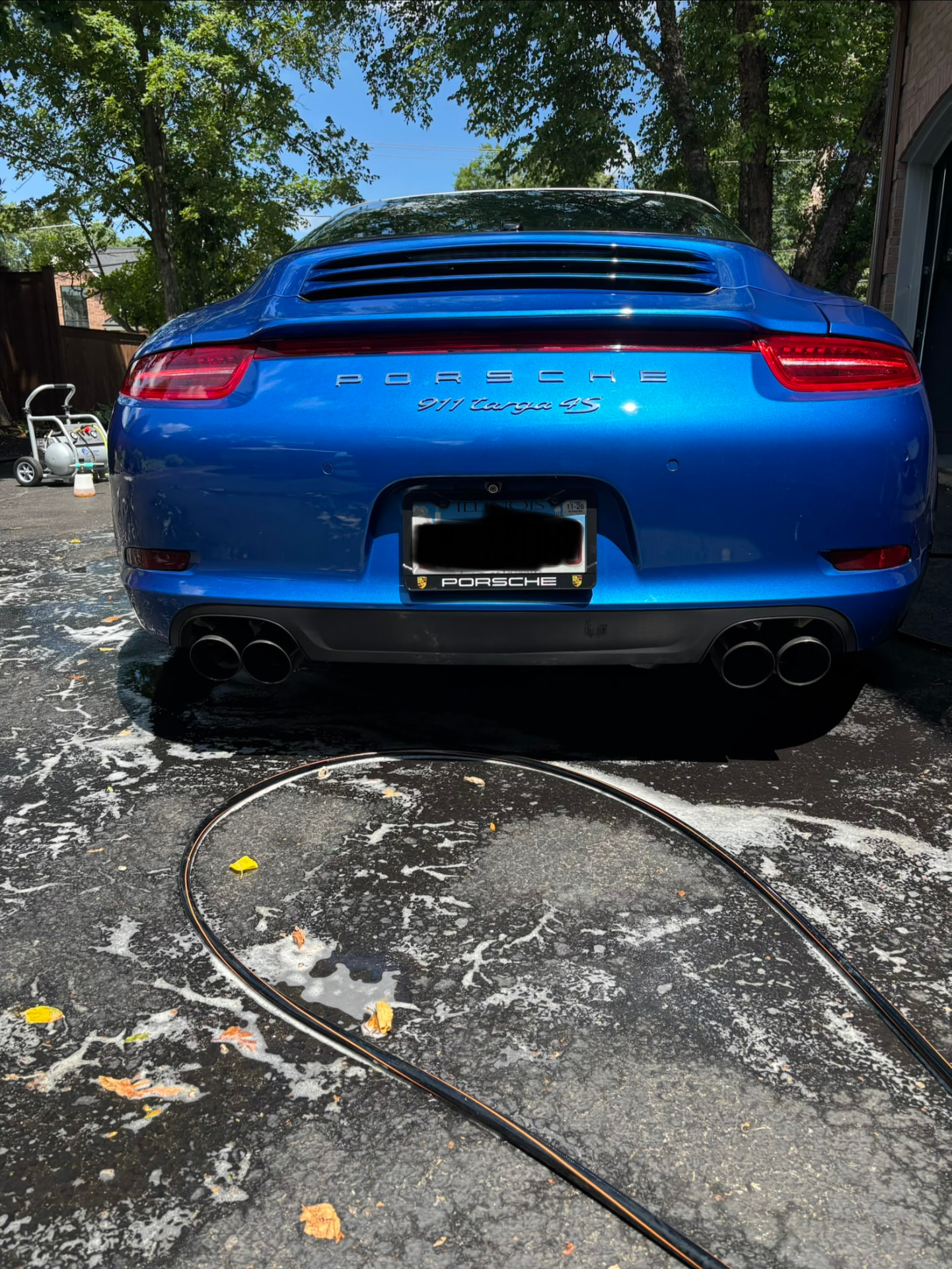 Blue Porsche 911 Targa 4S from behind on a driveway during a hand wash by Lucent Car Care