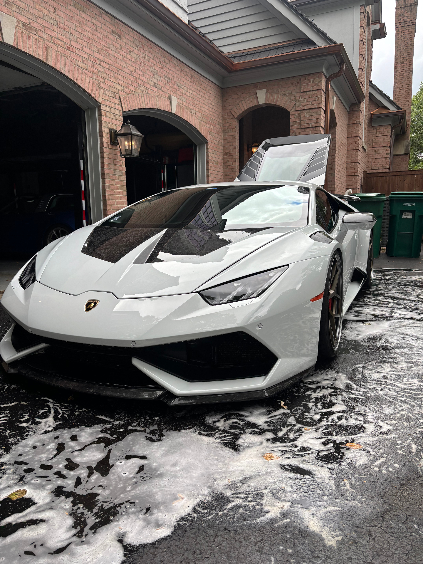 White Lamborghini Huracán with doors raised, exterior wash in progress