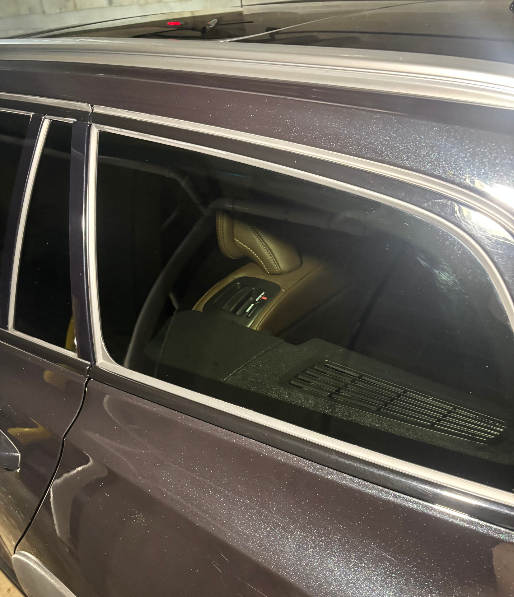 Car door window and interior trim after detailing, tan seats visible through glass