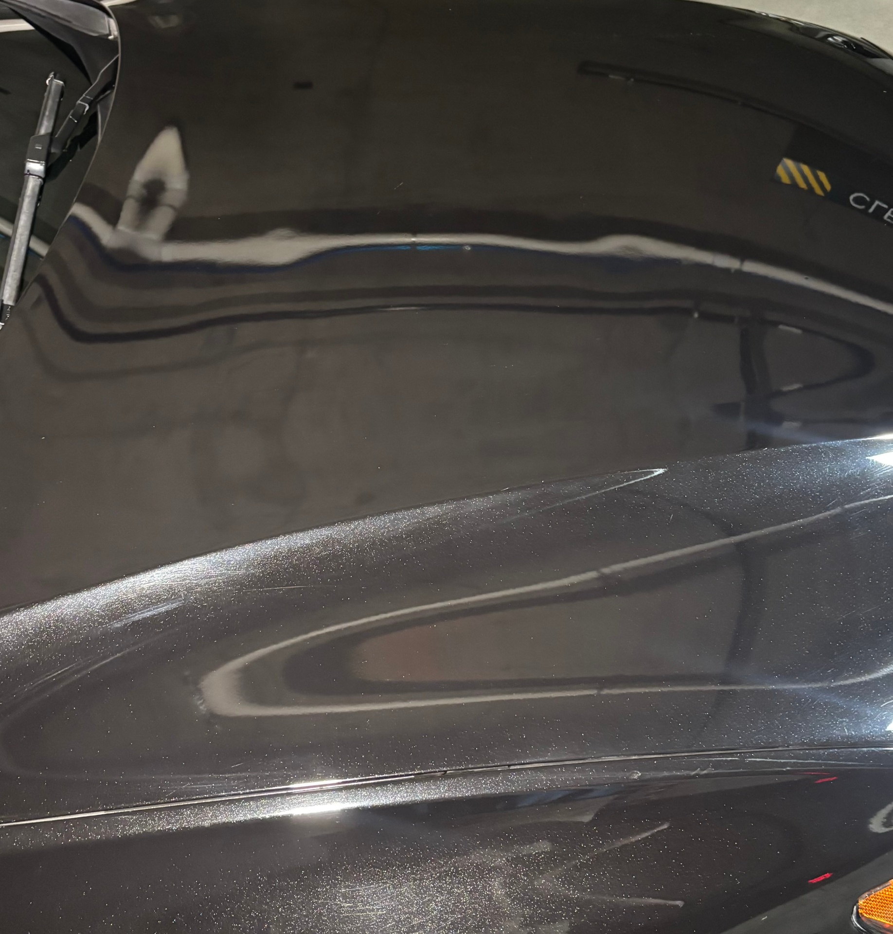 Glossy black car hood after wash and wax, showing reflective finish